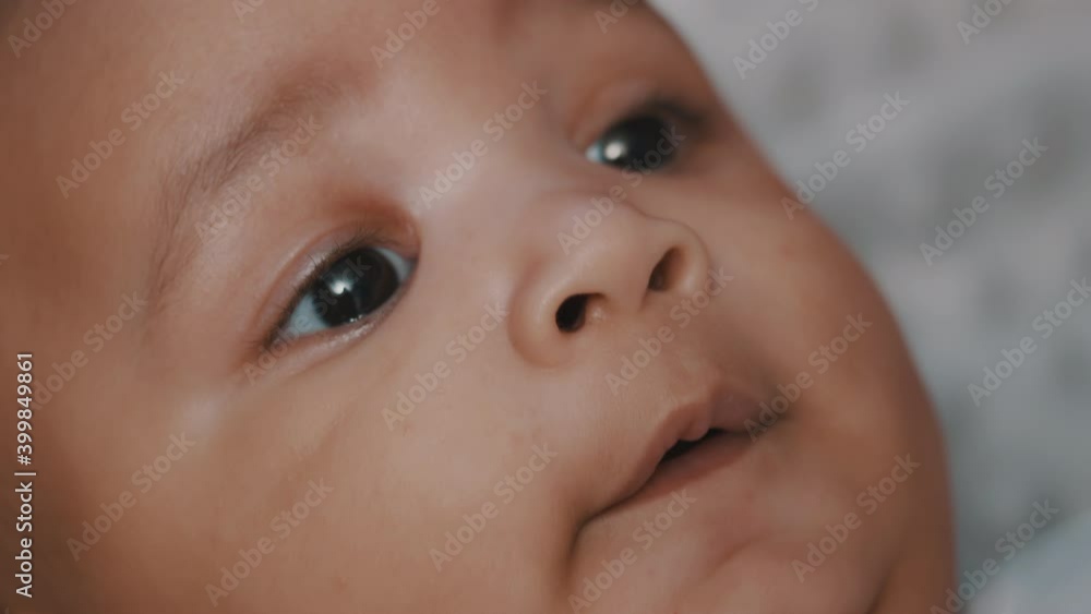 Happy newborn dark skin baby close up. Confused baby looking at the camera. High quality 4k footage Happy newborn dark skin baby close up. Confused baby looking at the camera. High quality 4k footage