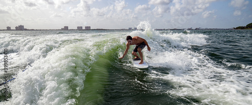 Man surfing skims the water with hand over a green wave photo