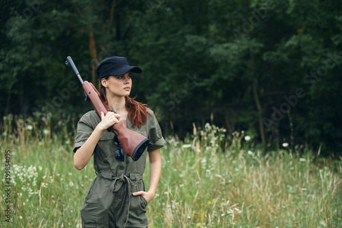 Military woman Arms on the shoulder hand in the pocket of a green jumpsuit green leaves 