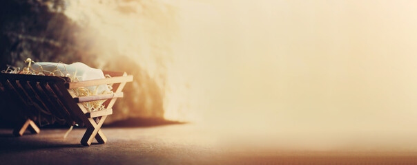 Nativity scene. Christian Christmas concept. Birth of Jesus Christ. Wooden manger in cave background. Banner, copy space. Jesus is reason for season. Salvation, Messiah, Emmanuel, God with us. Gloria