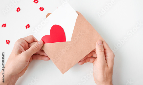 An open envelope with white paper and a red heart. A man holds a gun. photo