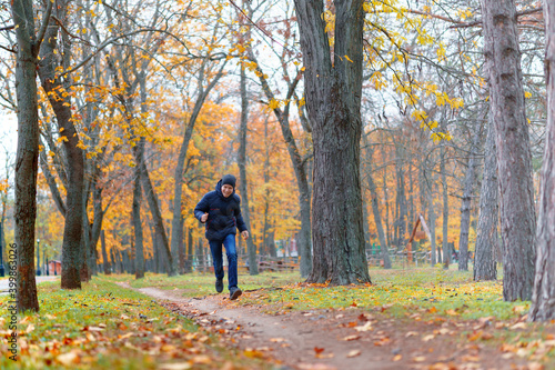 a boy running through the park and enjoys autumn, beautiful nature with yellow leaves