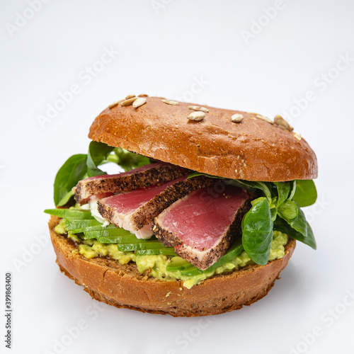 Bagel with tuna and greens on white background. 