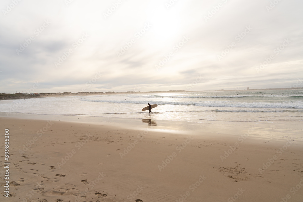 surfer gets out of the water on a beautiful sandy beach after an awesome surf session