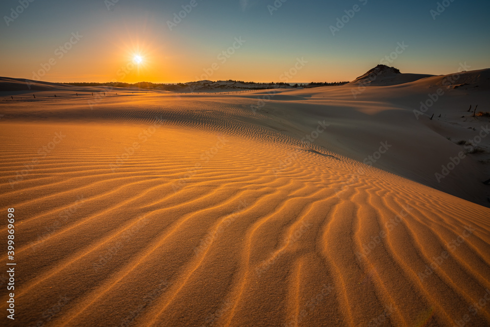Moving dunes in the Słowiński National Park during sunset. Amazing textures on sand bathed in golden light.
