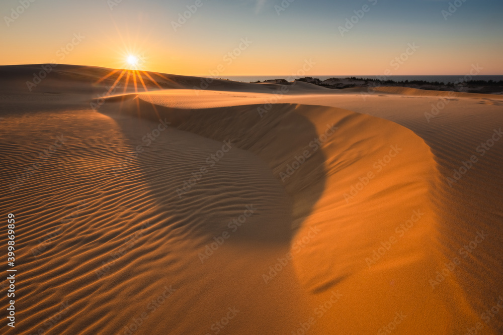 Moving dunes in the Słowiński National Park during sunset. Amazing textures on sand bathed in golden light.