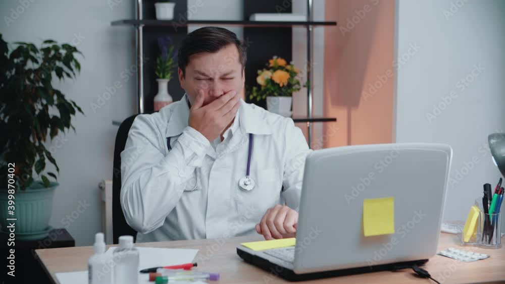 The doctor at his desk yawns with fatigue.Health concept. The doctor at his desk yawns with fatigue.Health concept.