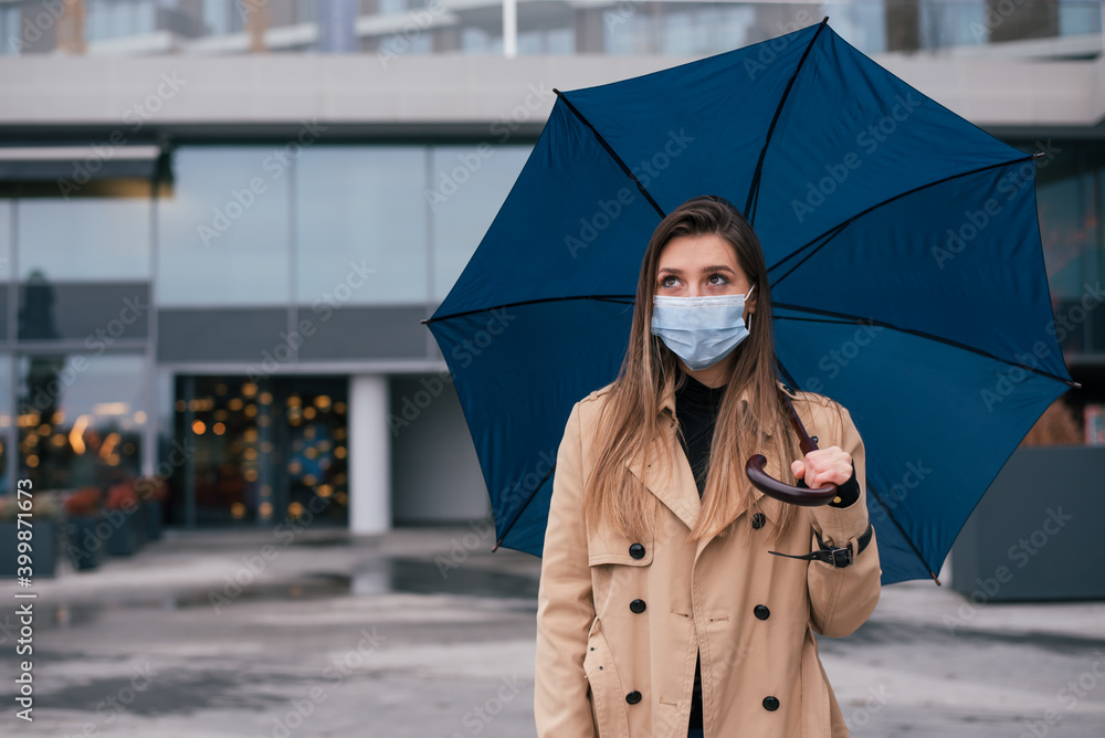 Woman wearing medical protective mask and standing under umbrella Woman wearing medical protective mask and standing under umbrella