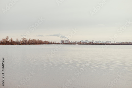 View of the city on the horizon behind the forest and the river.