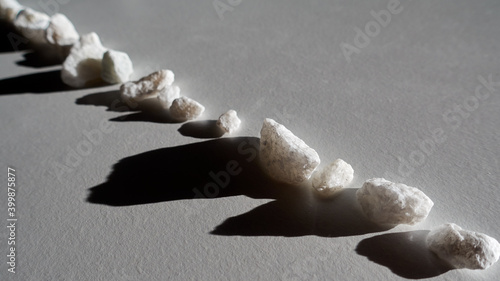 Photography A row of light stones with a shadow on a light surface.