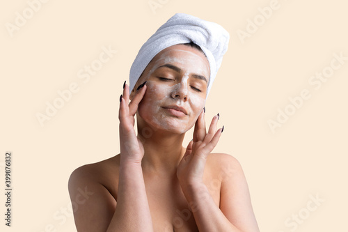 Beauty portrait of woman in white towel on head applies cream to the face. Skincare cleansing eco organic cosmetic spa relax concept.