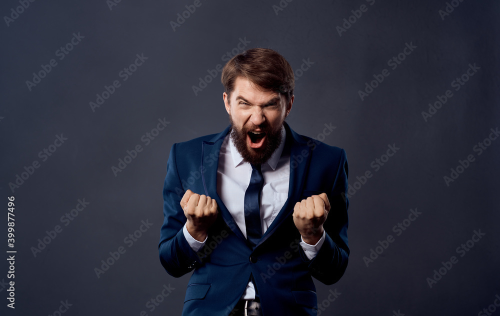 Emotional man in a suit gestures with his hands on a gray background energy model