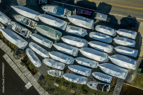Aerial view of winterized luxury boats dry docked in a marina covered with white wrapping looking like sardine fish swimming