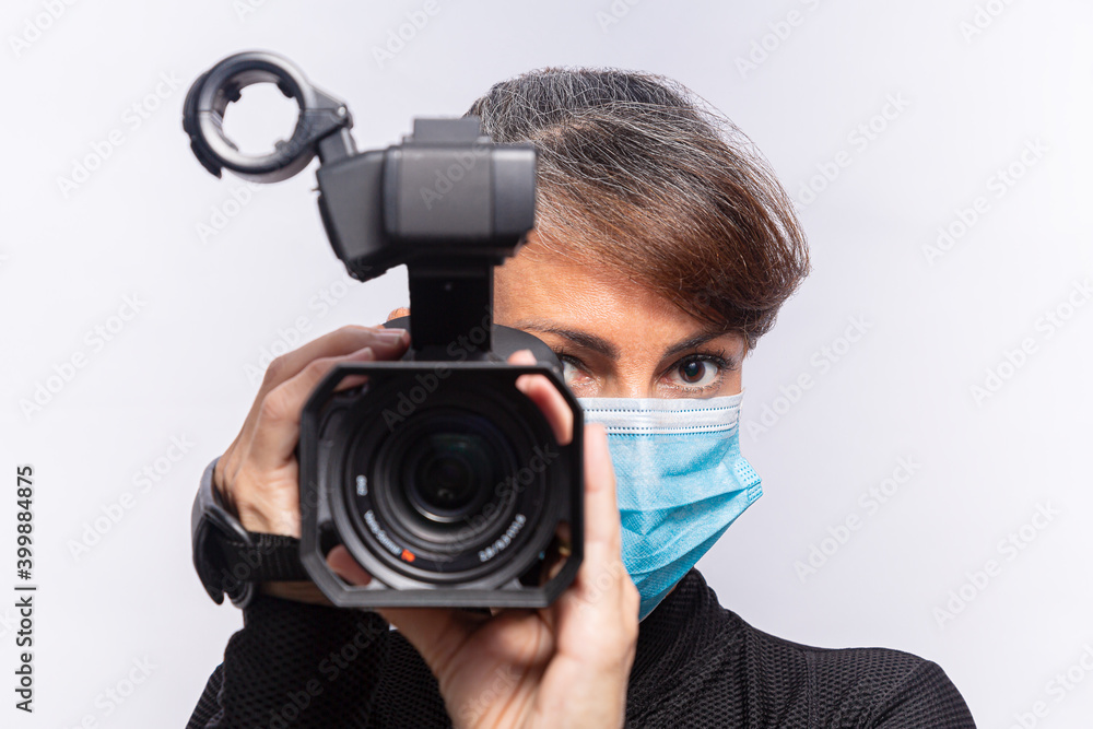 foco na mulher cinegrafista usando máscara cirúrgica com uma câmera de filmar e com as lentes fora de foco foco na mulher cinegrafista usando máscara cirúrgica com uma câmera de filmar e com as lentes fora de foco