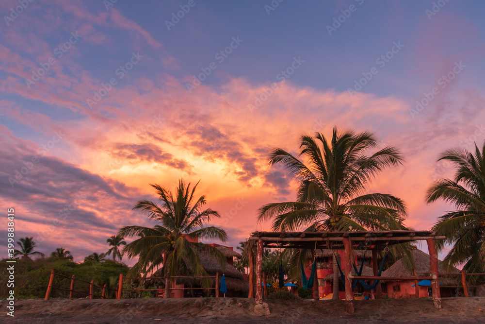 A vibrant tropical sunset on the beach in Mexico with Palm trees