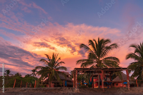 A vibrant tropical sunset on the beach in Mexico with Palm trees © Newman Photo