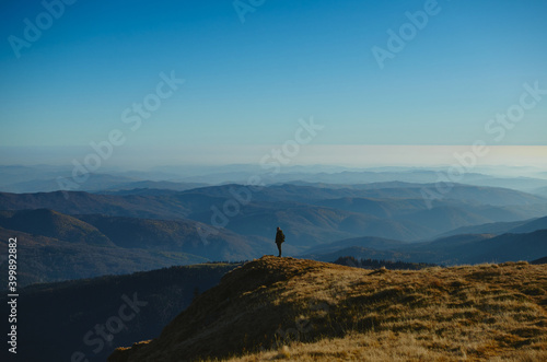 Man enjoying the autumn sunset on the edge of mountains. © chriscapatina