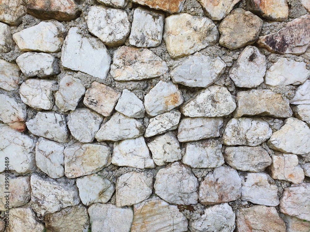Gray-white stone and granite - of various sizes, arranged neatly as a wall or fence. wall composes of various size of stone
