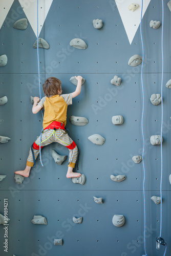 Preschooler boy scaling indoor homemade climbing wall. Home training during coronavirus pandemic