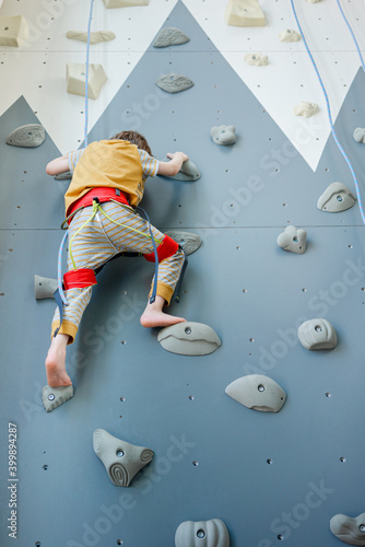 Preschooler boy scaling indoor homemade climbing wall. Home training during coronavirus pandemic
