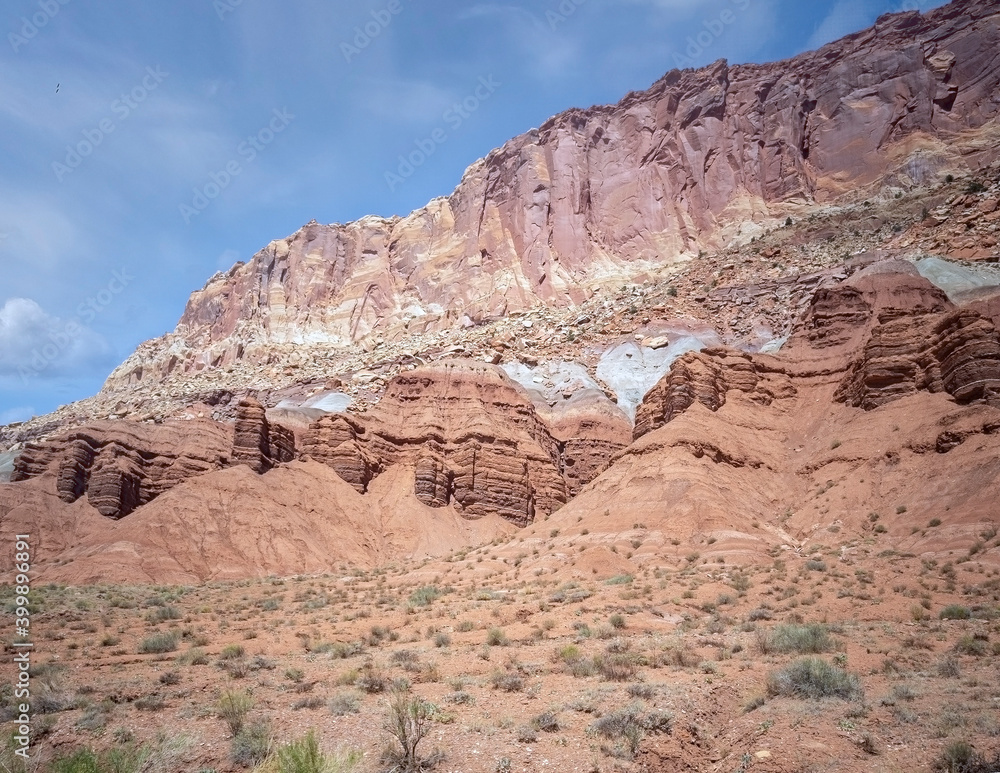Sublime monoliths and towering sandstone cliffs on a hot partly cloudy summer day at Capitol Reef National Park in Southern Utah.
