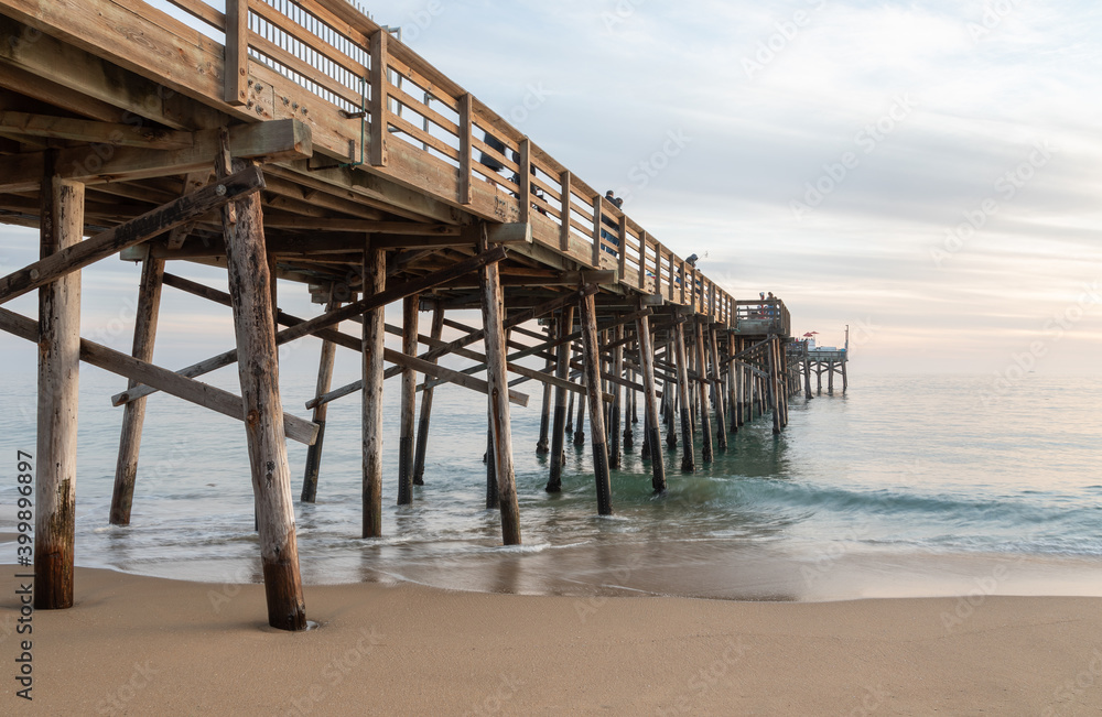 A gentle tide washes the sandy shoreline beneath the pier, just after sunset, at Balboa Peninsula, California. A gentle tide washes the sandy shoreline beneath the pier, just after sunset, at Balboa Peninsula, California.