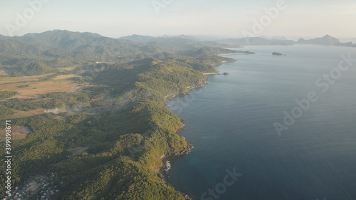 Mist over green mountains at ocean coast aerial. Philippines countryside with buildings, houses, cottages at palm trees. Nobody nature seascape and landscape of El Nido Island, Visayas Archipelago