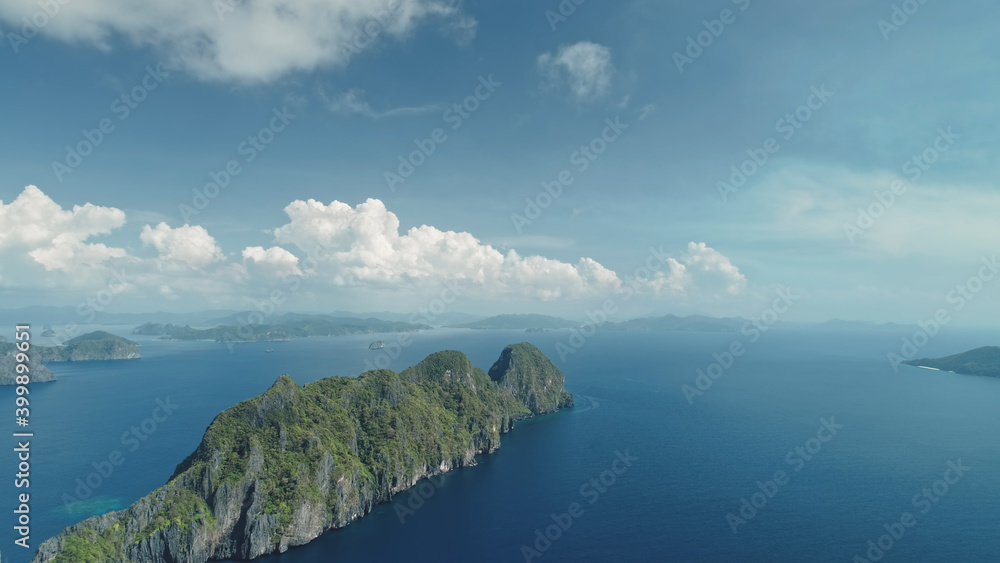 Fototapeta premium Mounts isles at blue water of ocean bay aerial view. Nobody nature seascape and island coastline under fluffy clouds at summer sunny day. Serene and relax of sea gulf waterfront at drone shot