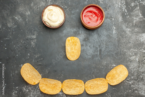 Snack party with delicious potato chips and mayonnaise and ketchup on gray background footage