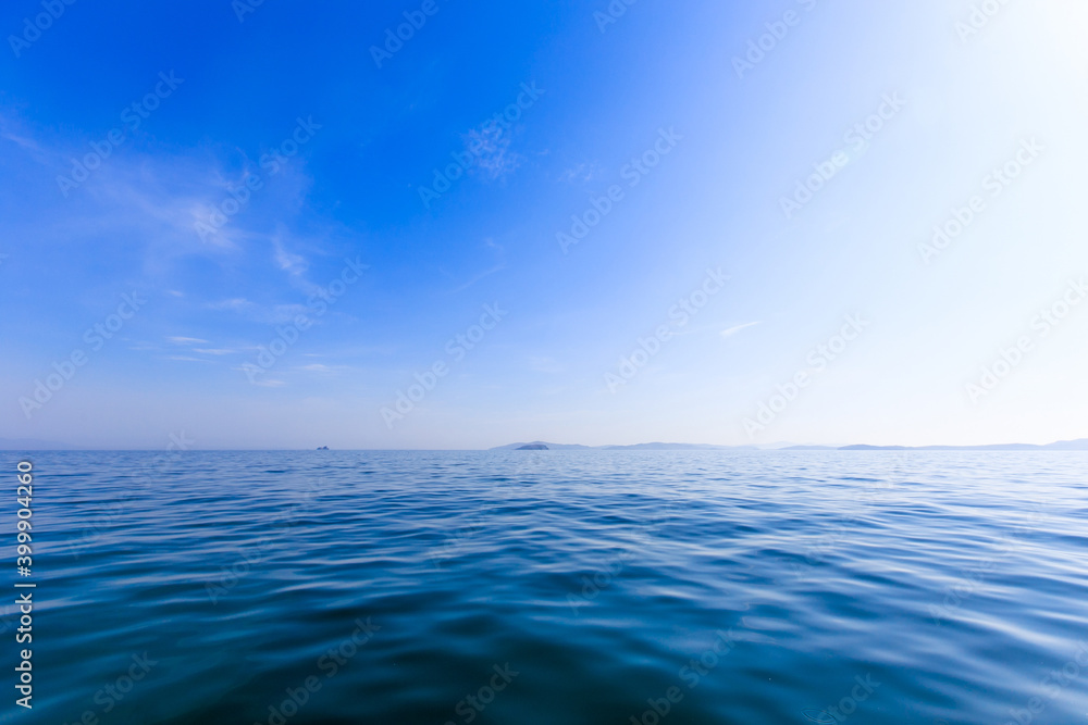 A small uninhabited green island in the middle of a calm blue sea and blue sky. Beautiful relaxation background. A small uninhabited green island in the middle of a calm blue sea and blue sky. Beautiful relaxation background.