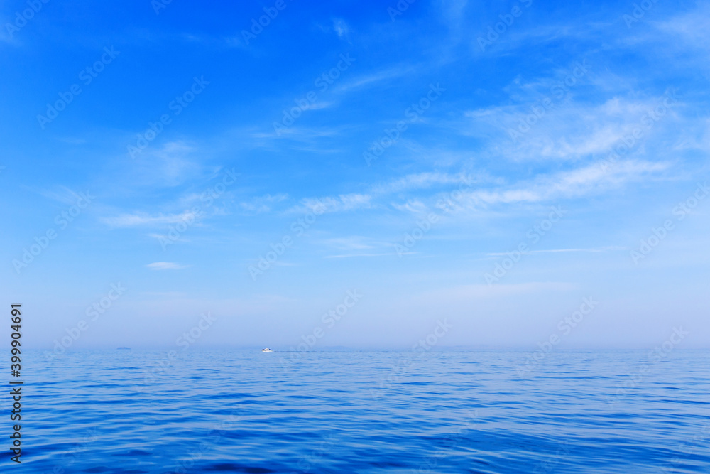 Beautiful relaxation background. A small white boat sits on a calm blue sea in clear weather. Calm at sea. Beautiful relaxation background. A small white boat sits on a calm blue sea in clear weather. Calm at sea.