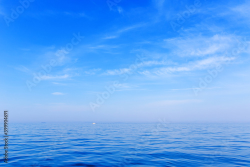 Beautiful relaxation background. A small white boat sits on a calm blue sea in clear weather. Calm at sea. © alexhitrov