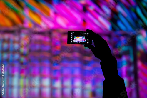 Silhouette of a hand with a phone photographing a light show