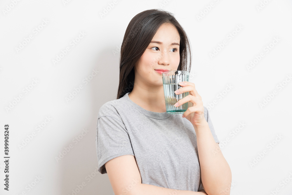 Beautiful portrait young asian woman smiling drinking a glass of water mineral on white background. Beautiful portrait young asian woman smiling drinking a glass of water mineral on white background.