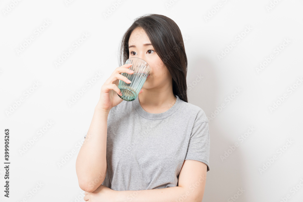 Beautiful portrait young asian woman smiling drinking a glass of water mineral on white background. Beautiful portrait young asian woman smiling drinking a glass of water mineral on white background.