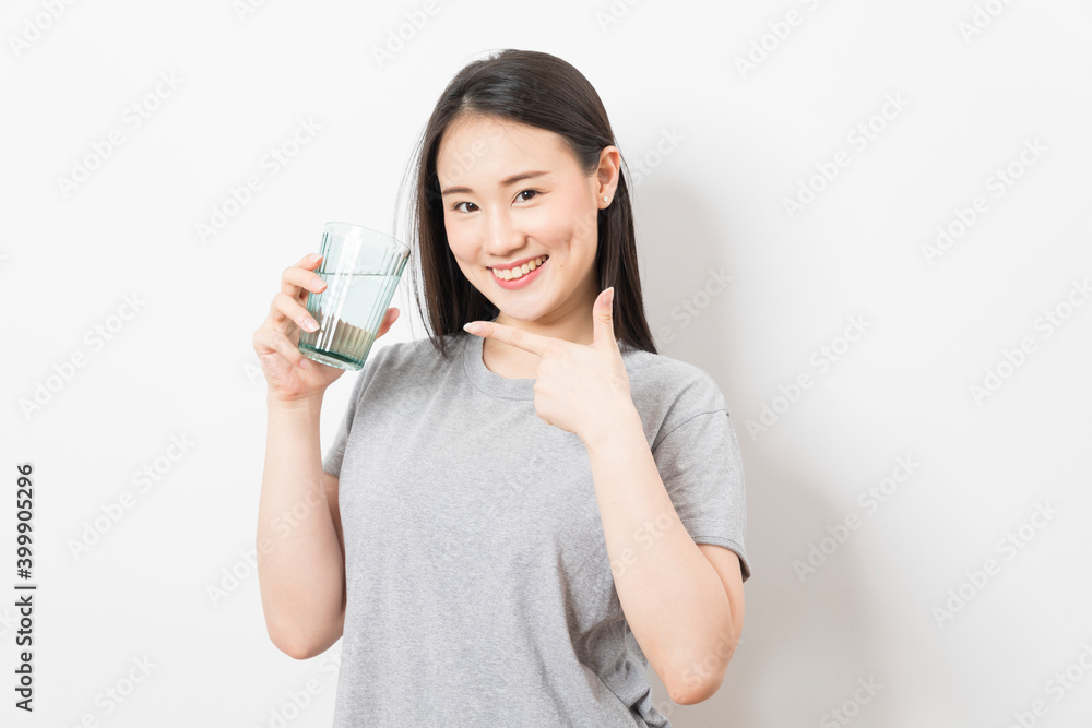 Beautiful portrait young asian woman smiling drinking a glass of water mineral on white background. Beautiful portrait young asian woman smiling drinking a glass of water mineral on white background.