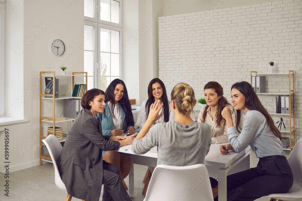 Fototapeta premium Smiling businesswomen sitting in circle at desk and planning projects together