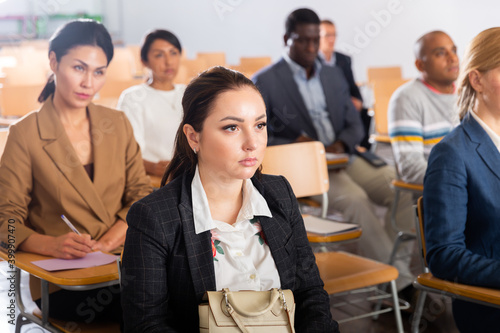 Portrait of positive attractive brunette attending business conference  listening with interest to speaker