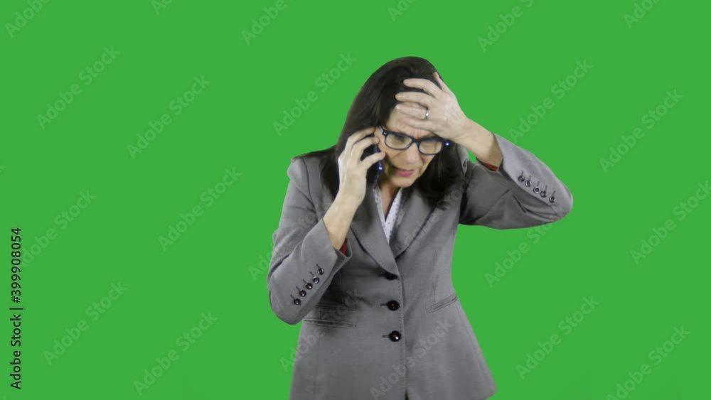 Angry mature businesswoman receives bad news while talking on her cell phone. The woman is devastated and upset she waves her arms and in desperation. She is wearing a suit and glasses on green screen Angry mature businesswoman receives bad news while talking on her cell phone. The woman is devastated and upset she waves her arms and in desperation. She is wearing a suit and glasses on green screen