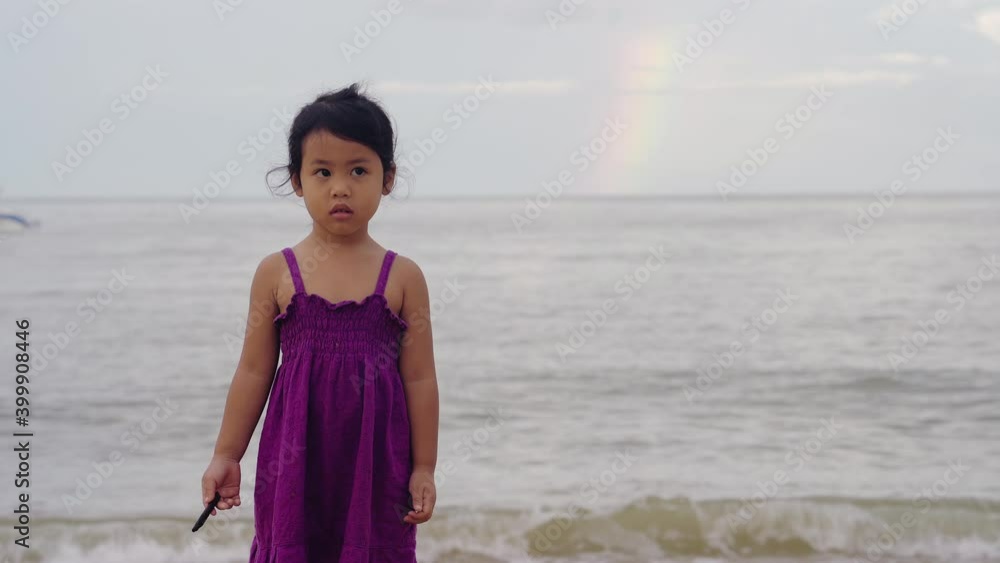 Cute little girl standing on sea shore against rainbow. Cute little girl standing on sea shore against rainbow.