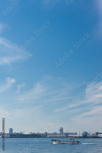 青空と名古屋港の海面で航海中の船の様子