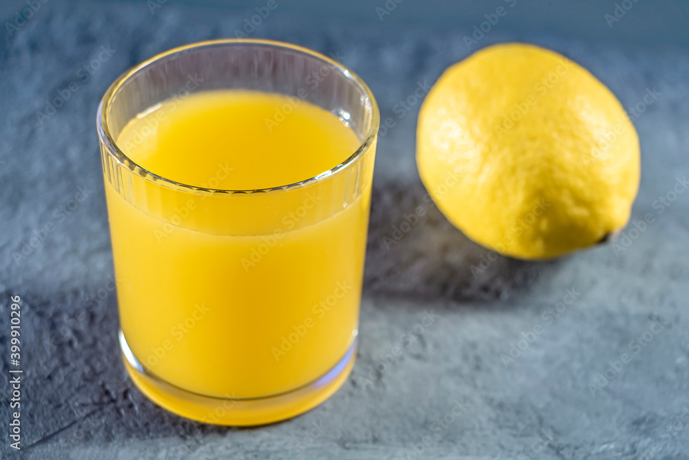 Glass with yellow lemon juice on gray background. Colors of Year 2021. Yellow-gray Glass with yellow lemon juice on gray background. Colors of Year 2021. Yellow-gray