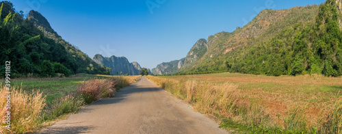 A rural road in the middle of the meadow in the beautiful mountains on a clear day in Thailand.