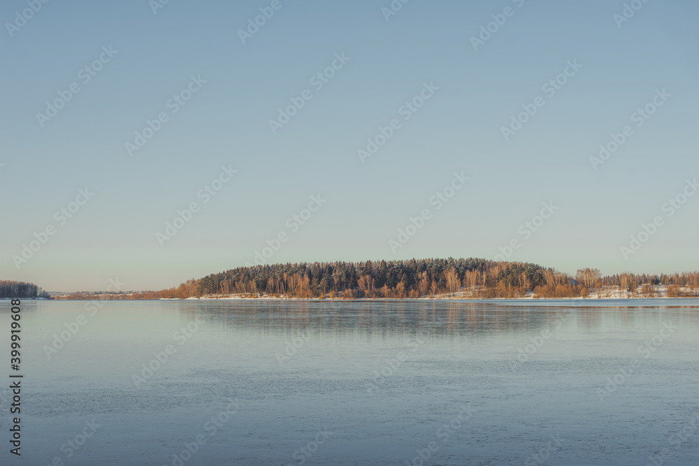 Frozen lake, clear transparent ice and frozen trees in a forest without foliage. Frozen lake, clear transparent ice and frozen trees in a forest without foliage.