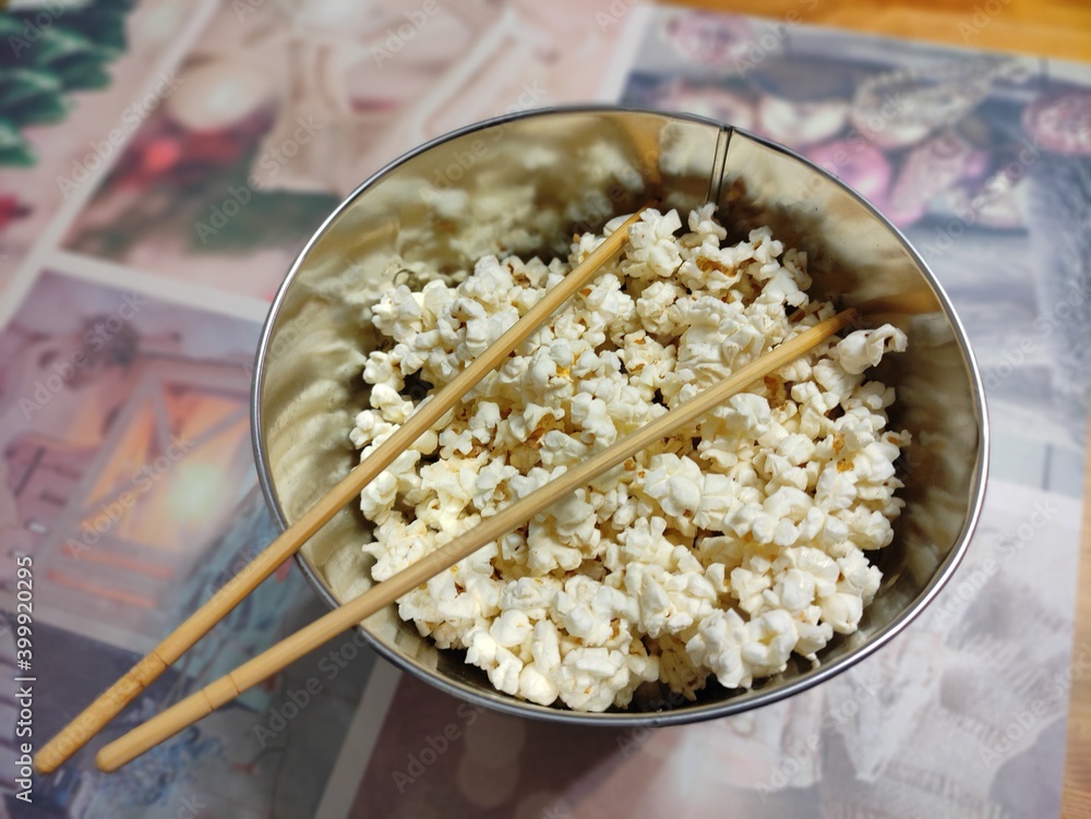 Obraz premium Ready popcorn in an iron bucket with spiderman on the kitchen table with chopsticks.