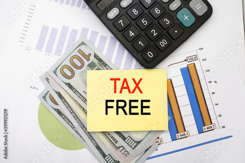 tax-free written on a piece of paper that lies on dollars and financial documents with a chart. Business and financial concept