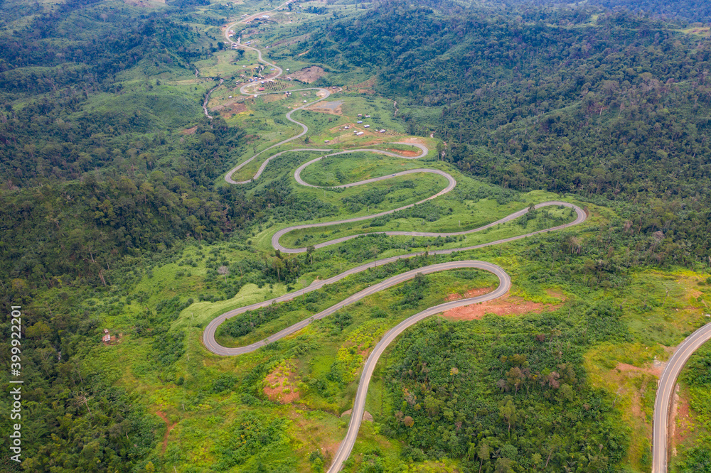 Winding road from the high mountain pass in Cambodia - Thailand Great road trip trough the dense woods. Aerial view.