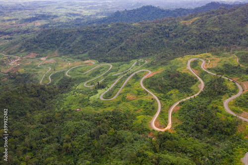 Fototapeta Naklejka Na Ścianę i Meble -  Winding road from the high mountain pass in Cambodia - Thailand Great road trip trough the dense woods. Aerial view.