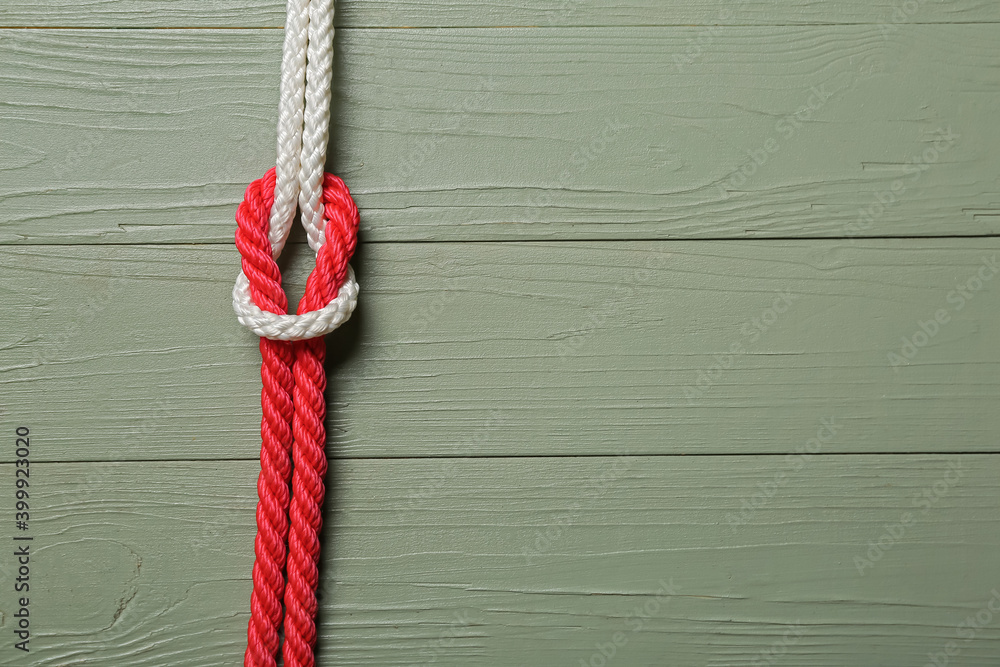 Rope with knot on color wooden background