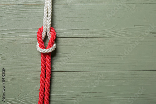 Rope with knot on color wooden background